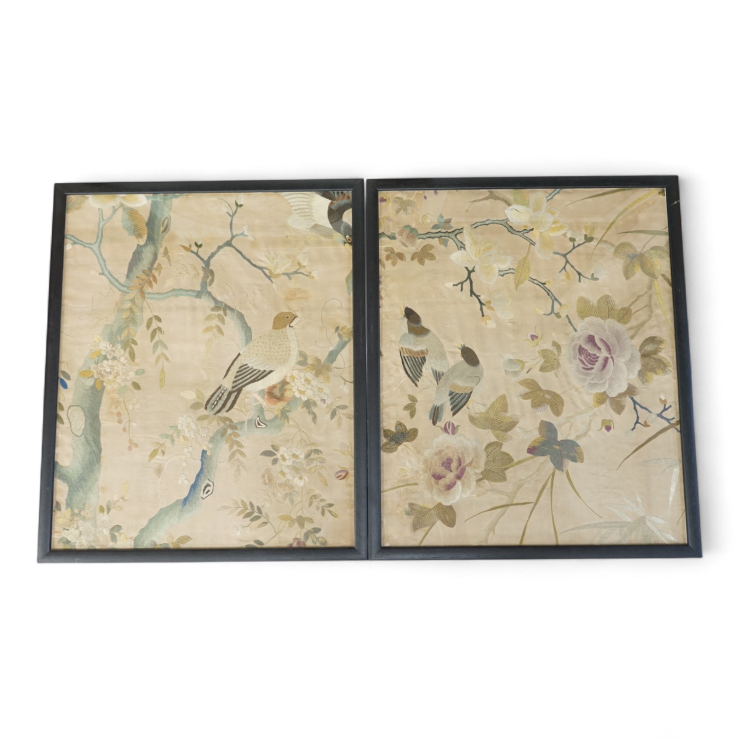 A pair of framed 19th century Chinese silk embroideries of exotic birds amongst entwined flowering branches, embroidered on a beige silk back ground, possibly cut from a larger embroidery. 47cm x 57cm., Condition - one f